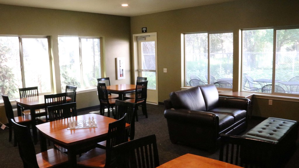 a dining room with couches tables and chairs and large windows