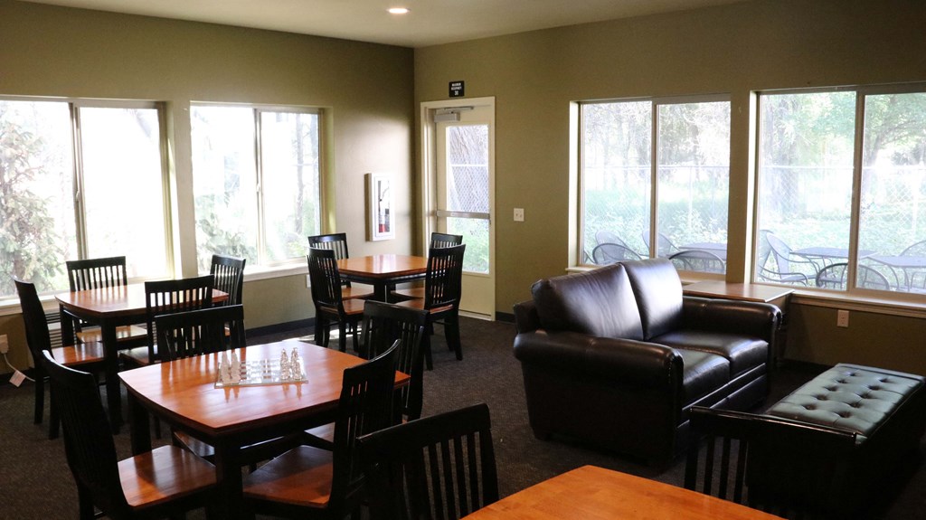 a living room with couches tables and chairs and large windows