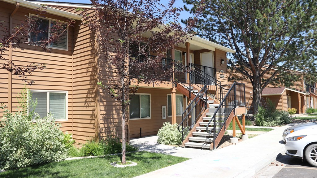 the front of a house with stairs and a car parked in front