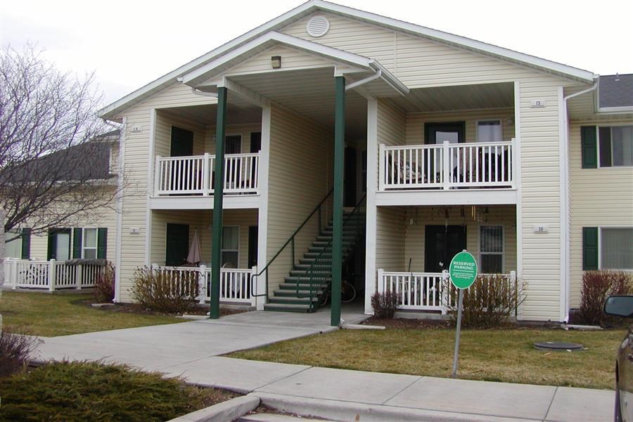 a white house with stairs and a green sign