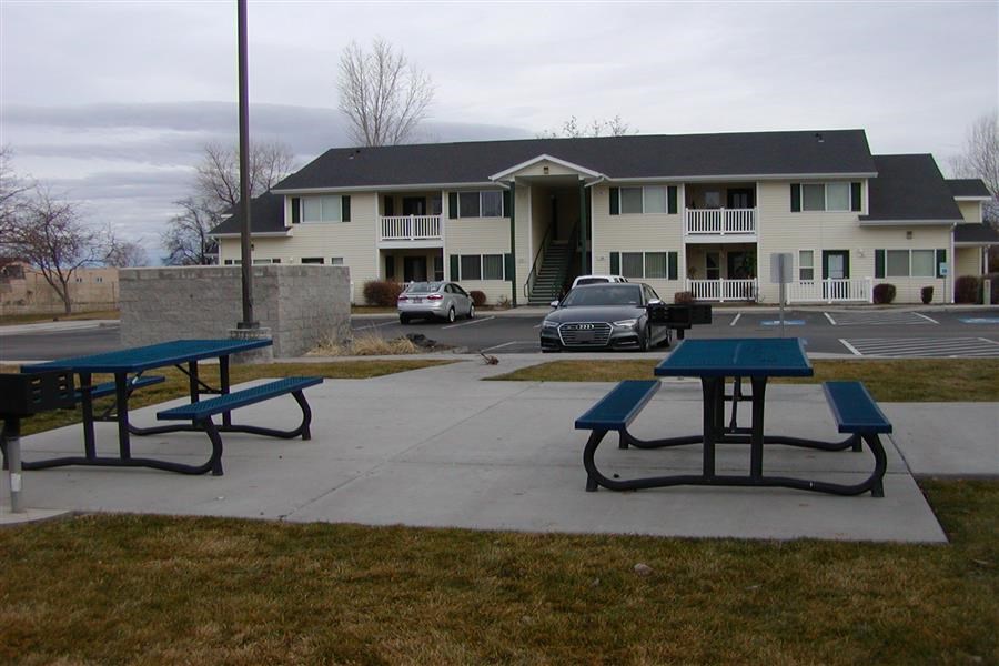 two picnic tables in front of an apartment building