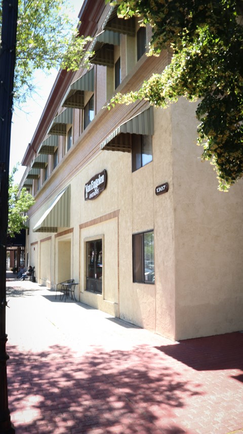 the outside of a building with a sidewalk and tree