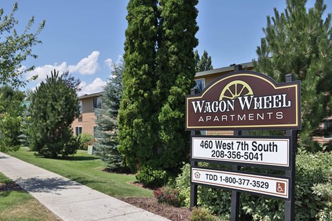 a sign for wagon apartments in front of a lawn and trees