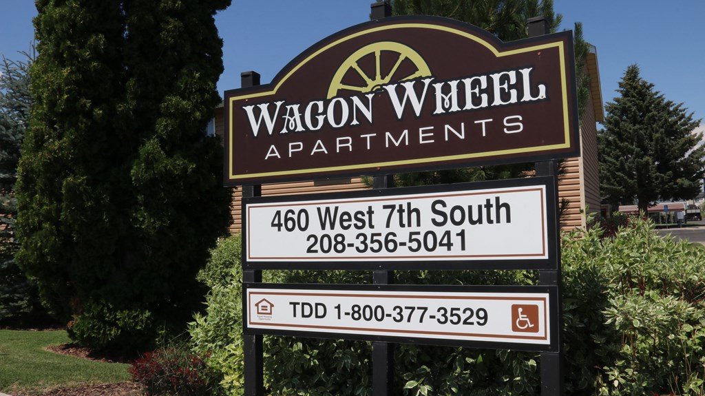 a sign for wagon apartments in front of a yard with trees