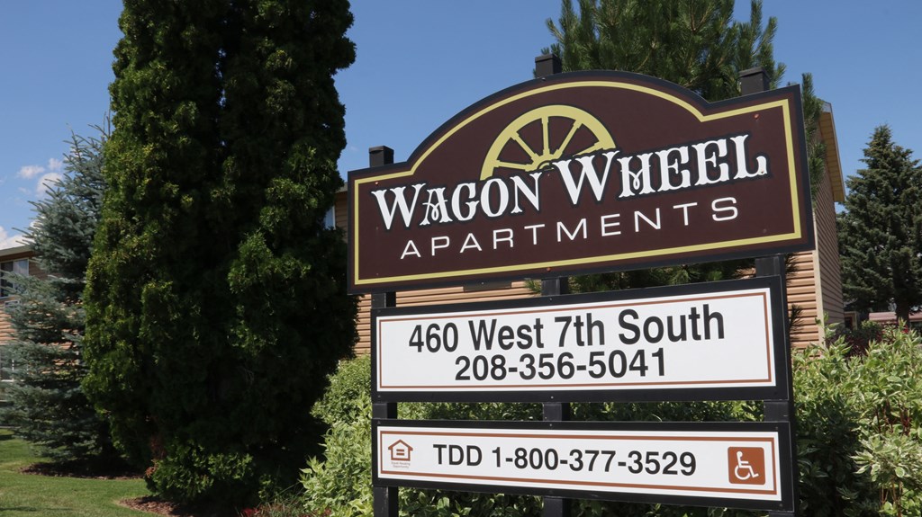 a sign for wagcon wheel apartments in front of a tree