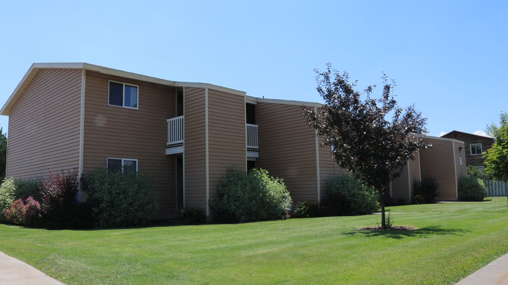 a brown apartment building with a lawn in front of it