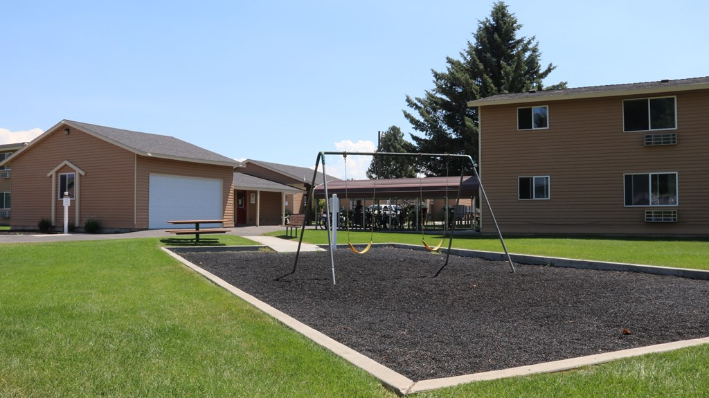 a swing set in a yard in front of two houses