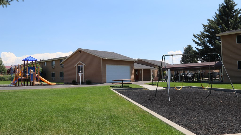 a playground in front of a house with a swing set