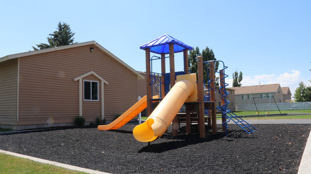 a playground with a slide in front of a house