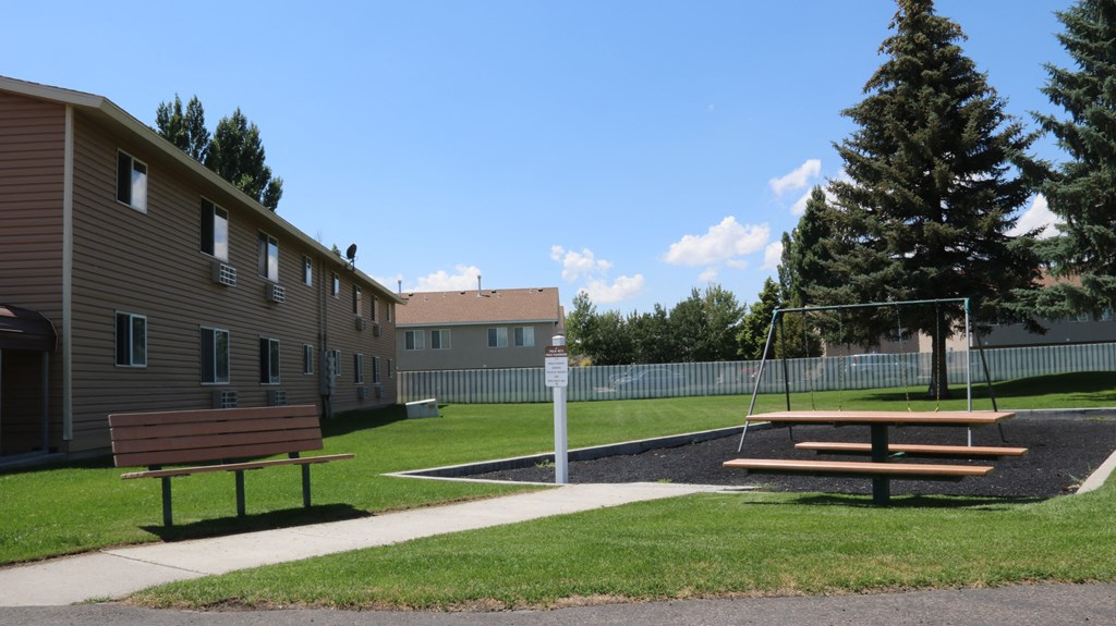 a park with a playground and picnic tables