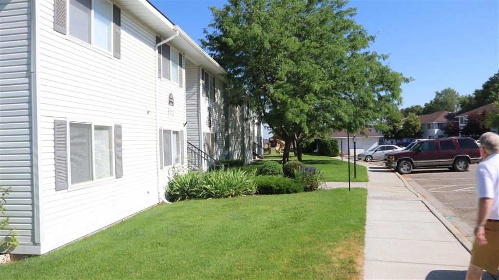 a man walking down a sidewalk in front of a white house
