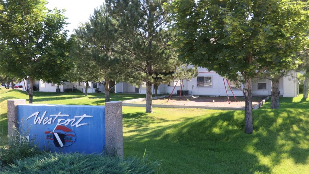 a blue sign sitting in the grass near trees