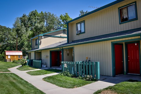the front of a house with a green fence and a red door