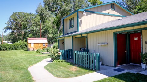 the front of a yellow house with a red door    and a shed