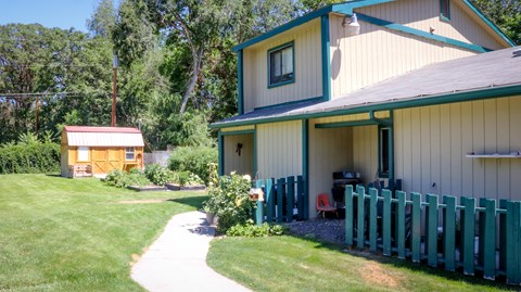 the side of a house with a green fence and a shed