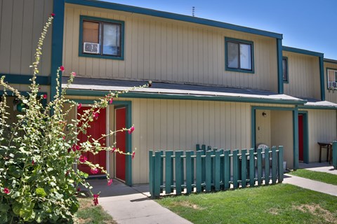the front of a house with a green fence and a red door