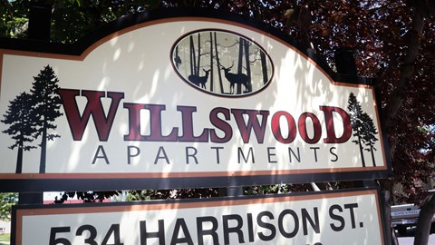 a sign that says wildwood apartments in front of a tree