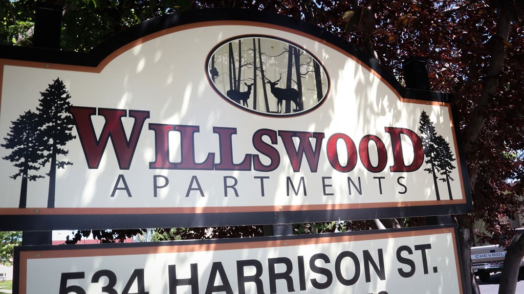 a sign that says wildwood apartments in front of a tree