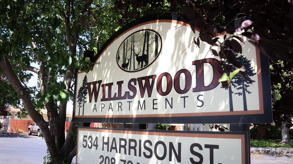 a sign for millwood apartments in front of a tree
