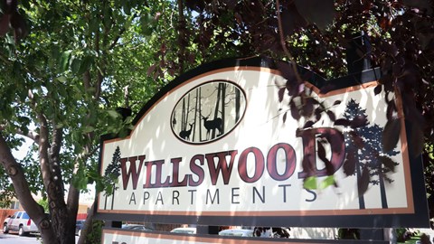 a sign for willwood apartments in front of trees