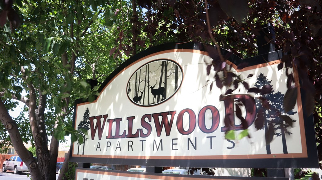 a sign for willwood apartments in front of trees
