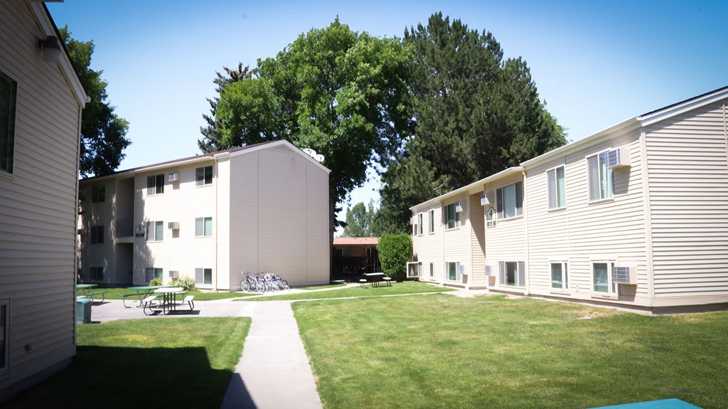 a group of apartments with a lawn and trees
