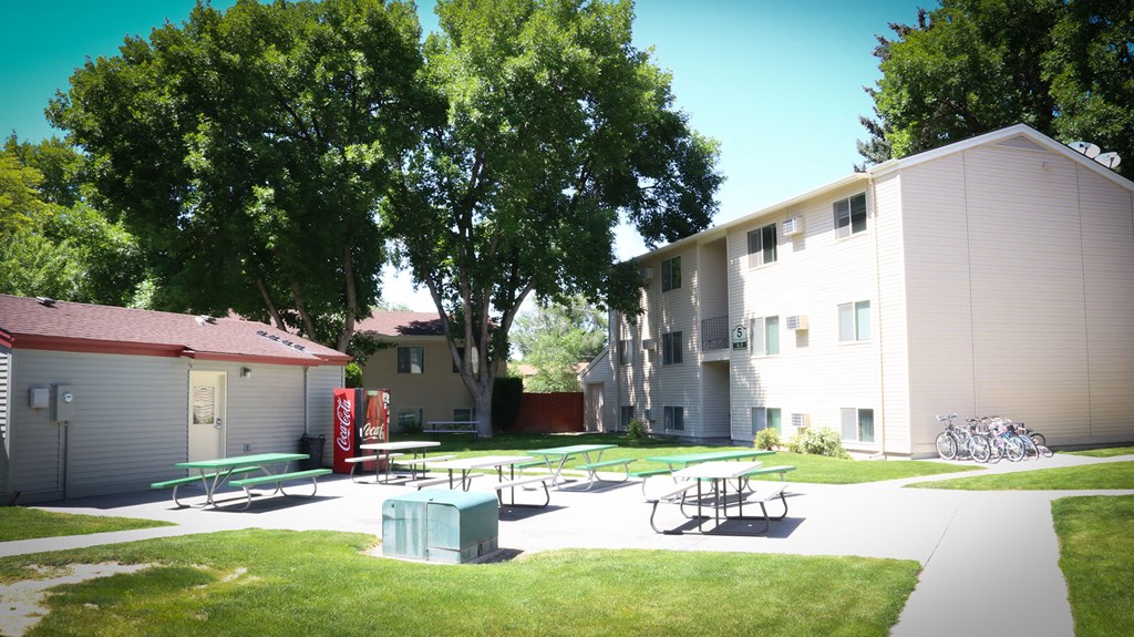 an outdoor area with picnic tables in front of some apartments
