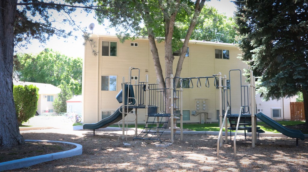 a playground in a park in front of a yellow house