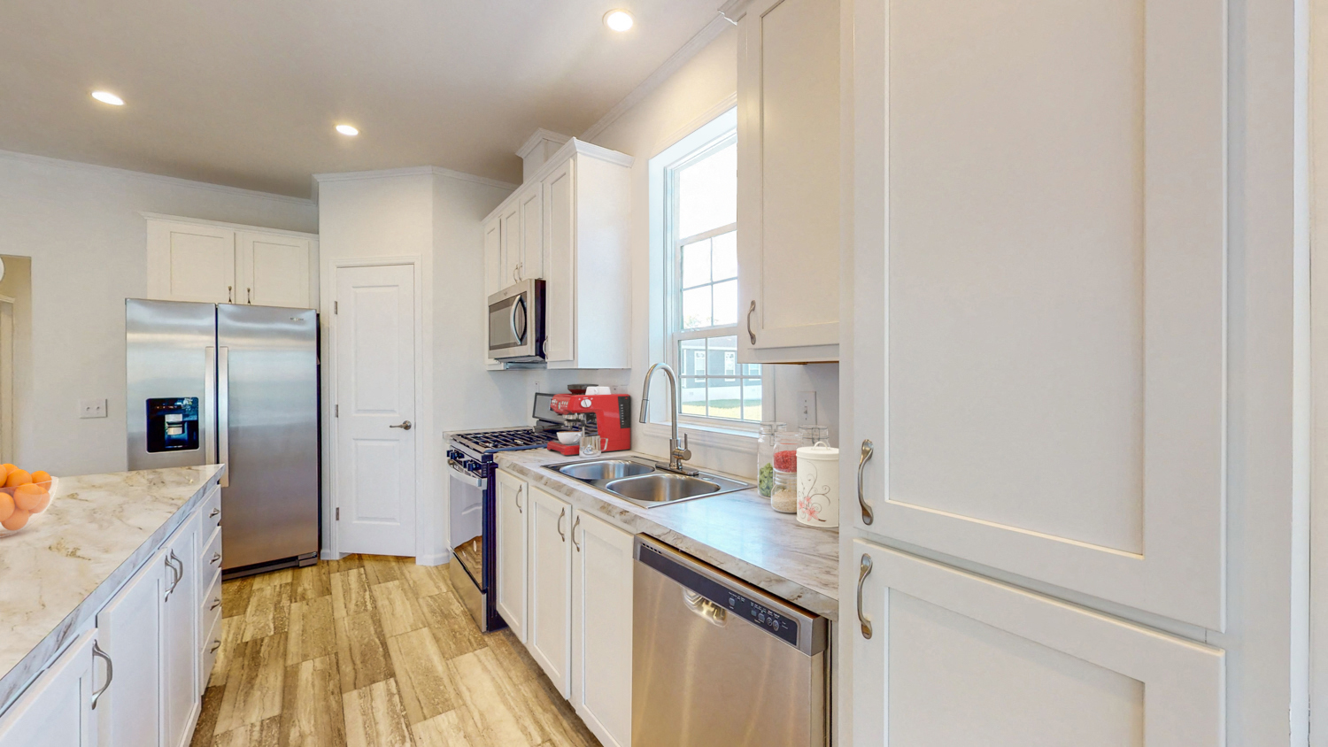 a white kitchen with stainless steel appliances and white cabinets