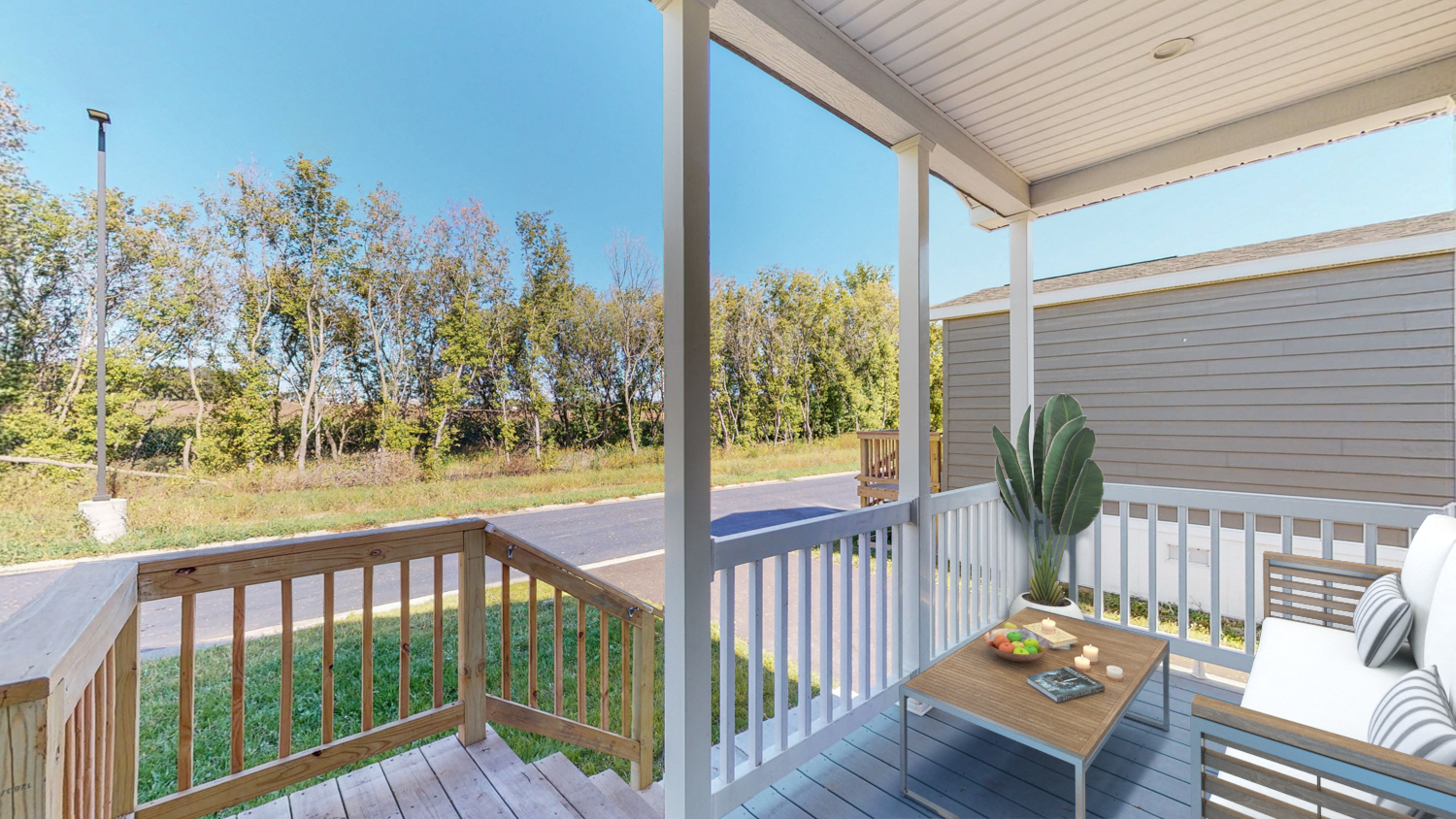 a covered porch with a table and chairs and a view of a yard and trees