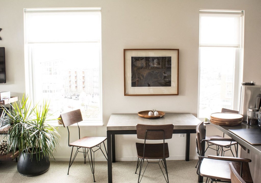 a dining room with a table and chairs and a painting on the wall