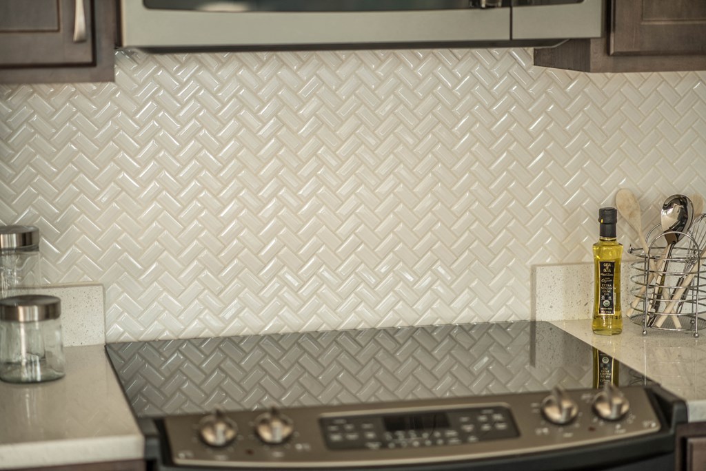 a kitchen with white subway tile and a stove top oven