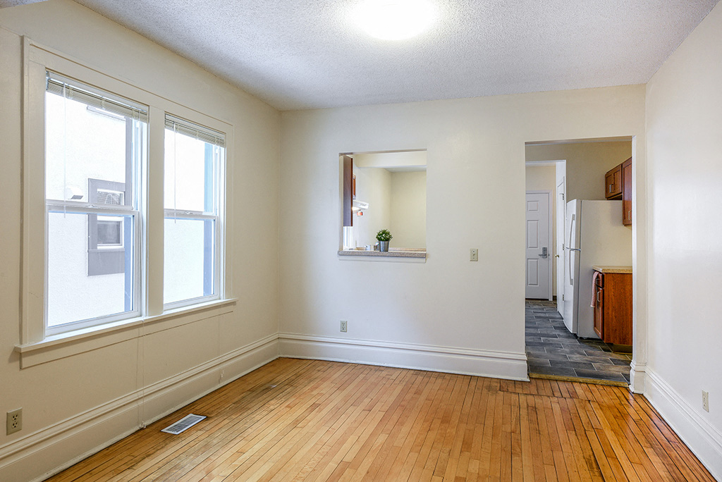 an empty living room with a hard wood floor and large windows