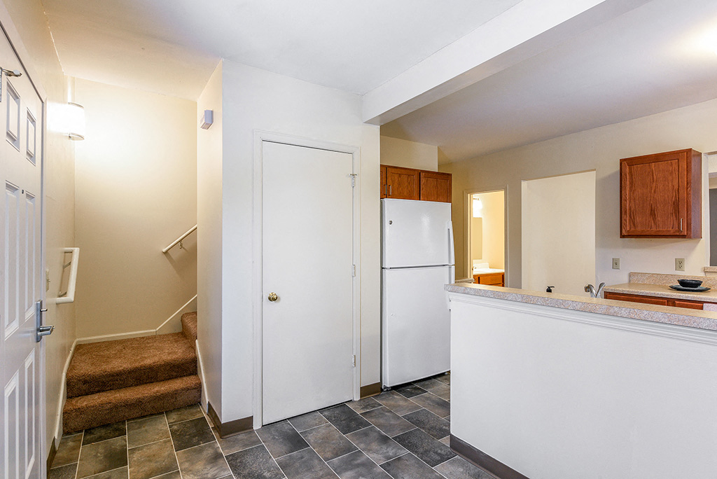 a kitchen with a white refrigerator and a staircase