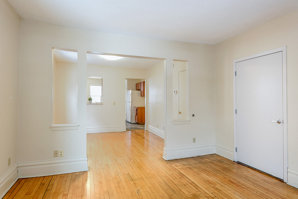 the living room and dining room of an empty house with wood floors and white walls