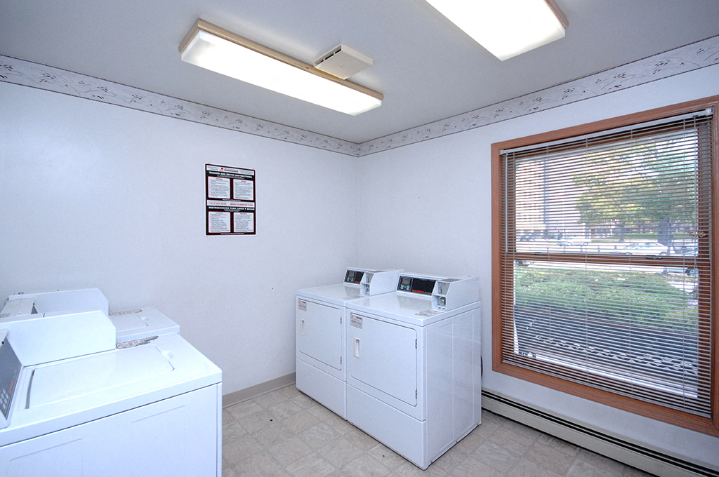 a laundry room with two washer and dryers and a large window