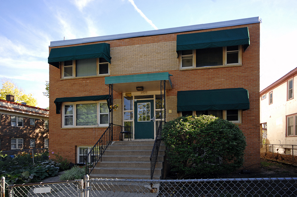 an old brick house with green awnings and stairs