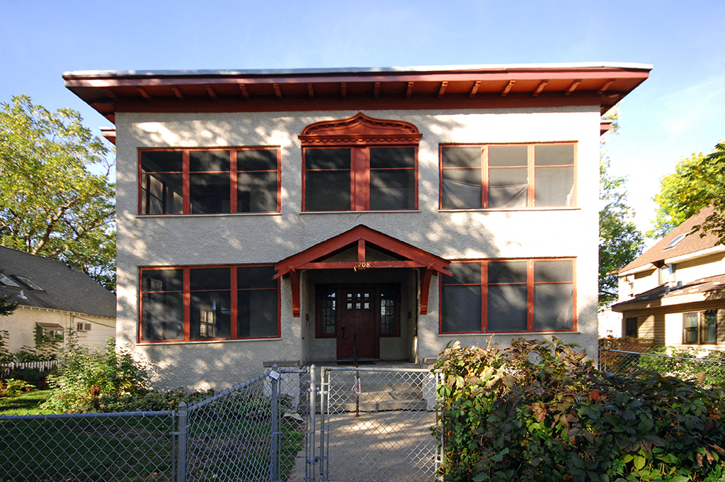 a white house with a red roof and a gate