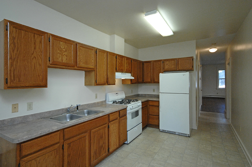 an empty kitchen with wooden cabinets and white appliances