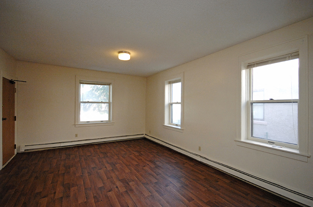 the living room of an empty house with wood floors and two windows