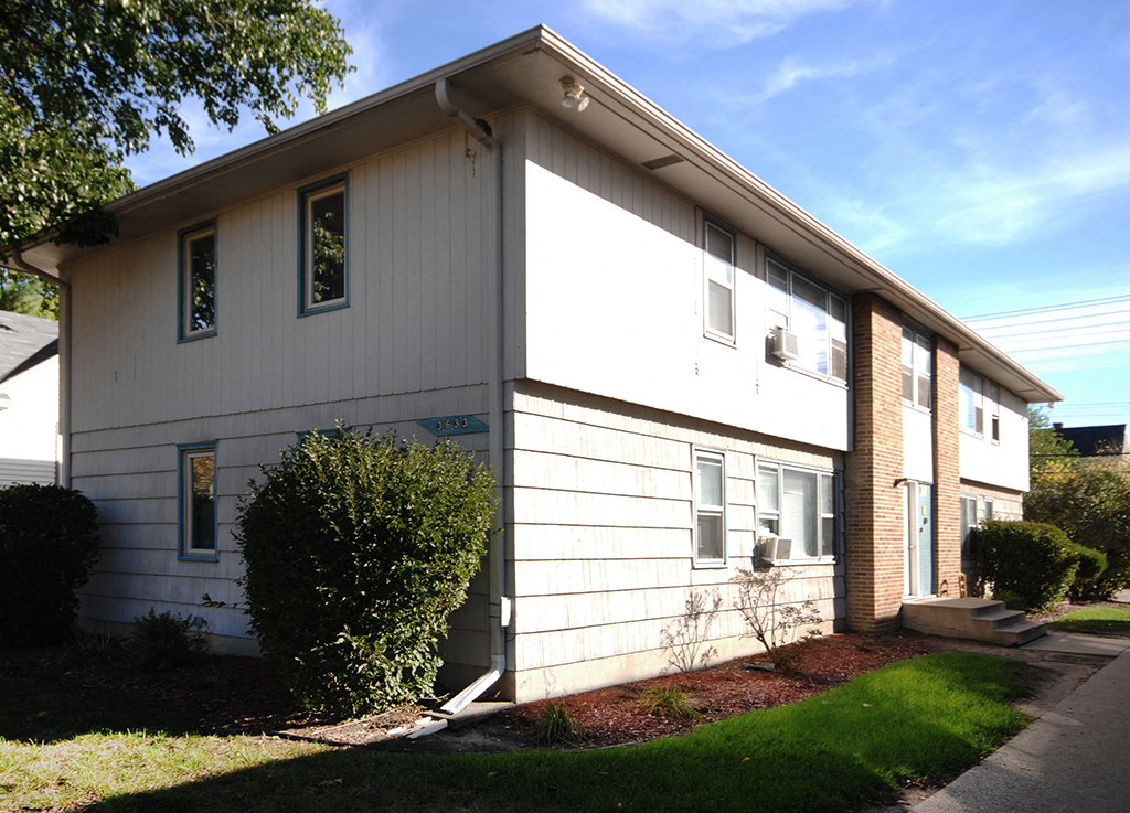 a white house with white siding and a sidewalk