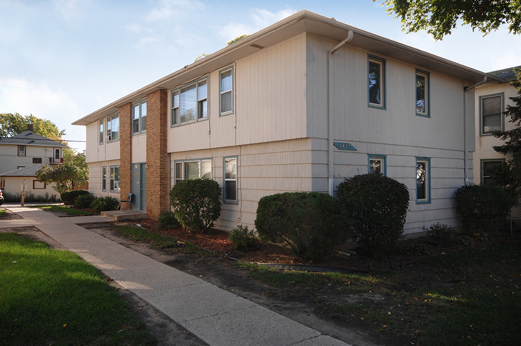 an apartment building with a sidewalk in front of it