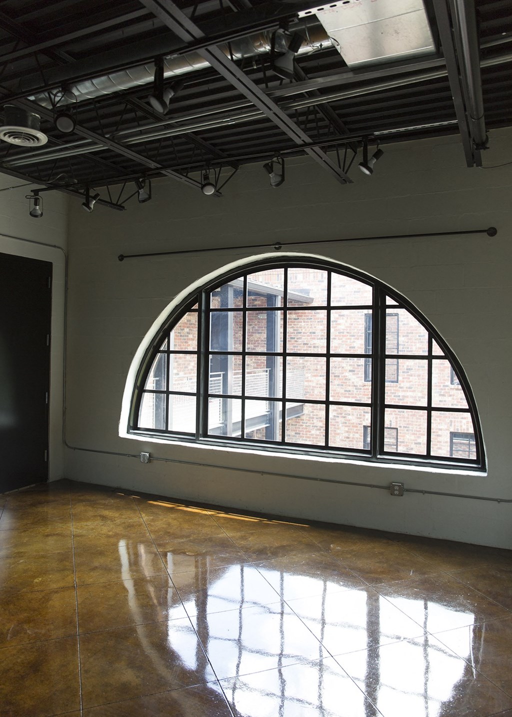 an arched window is reflected in the floor of an empty room