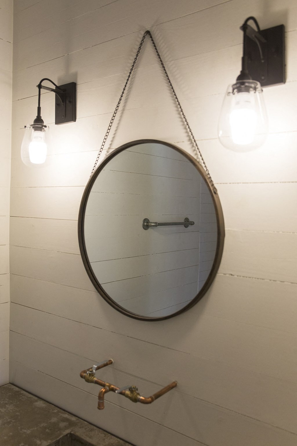 the mirror hangs on the wall with two lights above it