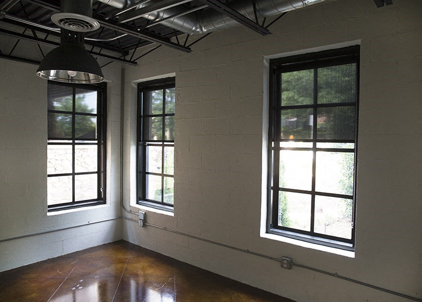 an empty room with two windows and a light fixture
