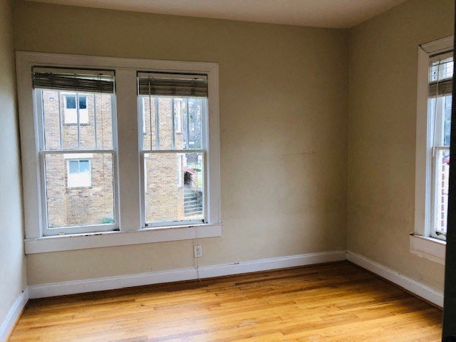 an empty room with two windows and a wooden floor