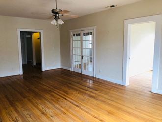 an empty living room with wood floors and a ceiling fan