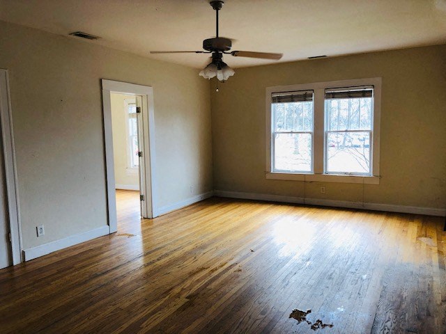an empty living room with wood floors and a ceiling fan