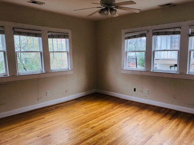 an empty living room with wood floors and a ceiling fan