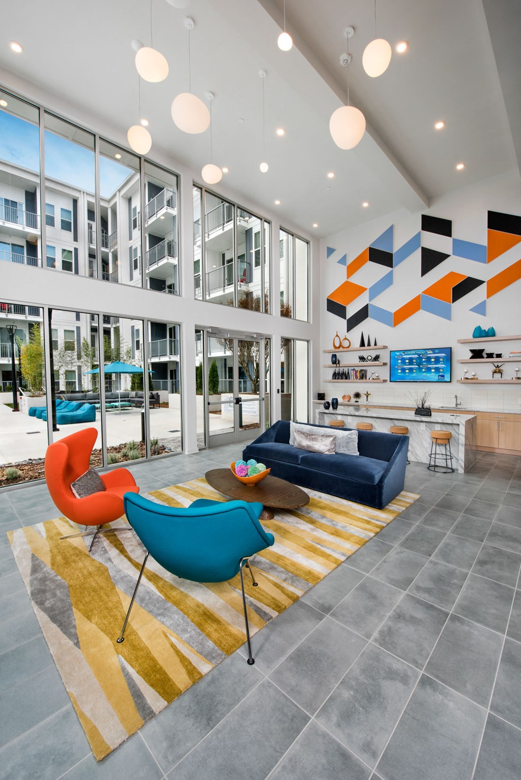 a living room with blue couches and chairs in front of large windows
